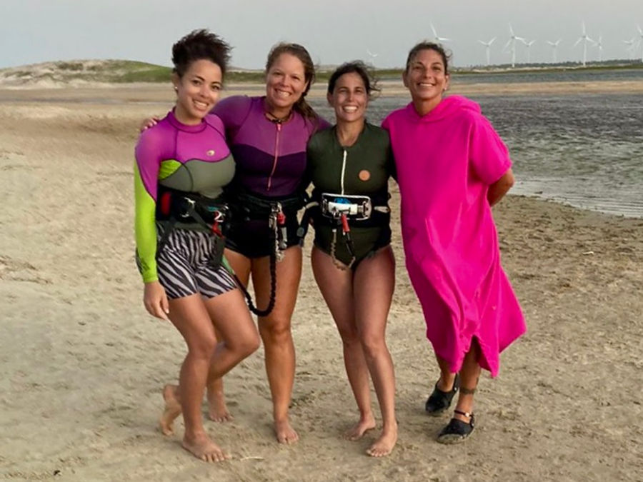 Four riders in colourful kite gear walking the beach