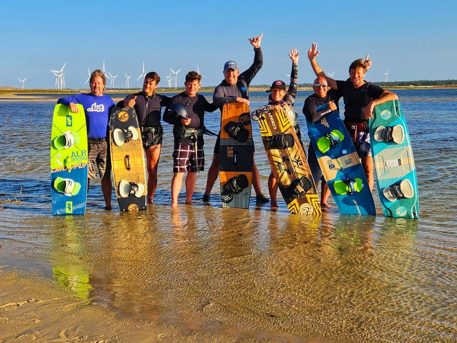 Riders standing in shallow flat water with their boards