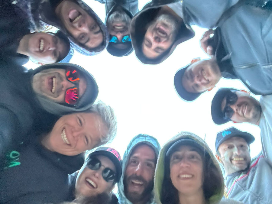 Circle of smiling EK Experience riders looking down at the camera