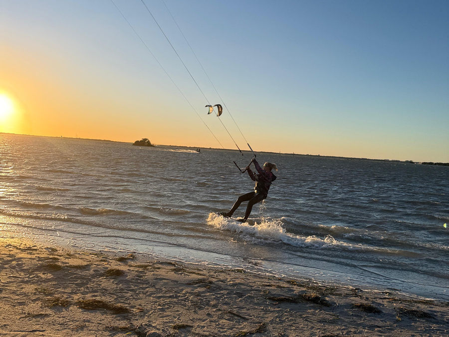 Kiteboarder riding into a golden sunset