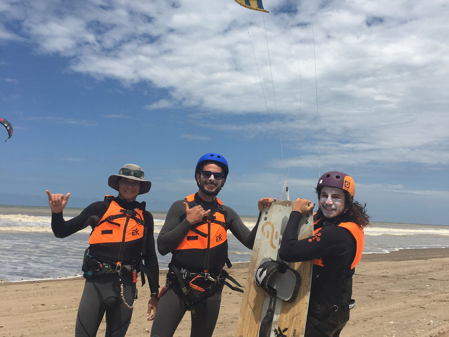 Three riders with a board on the beach after a lesson