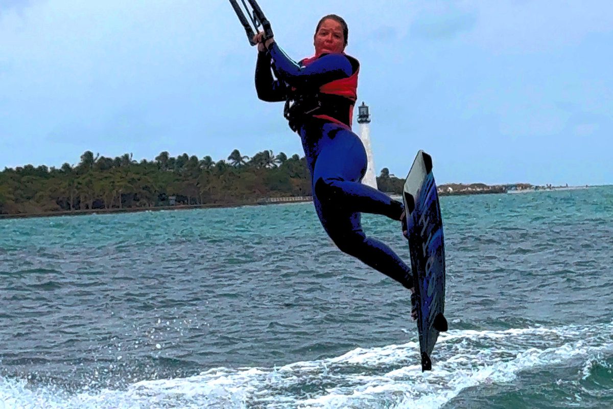 Intermediate kiteboarder catching air off flat water during an EK Experience session